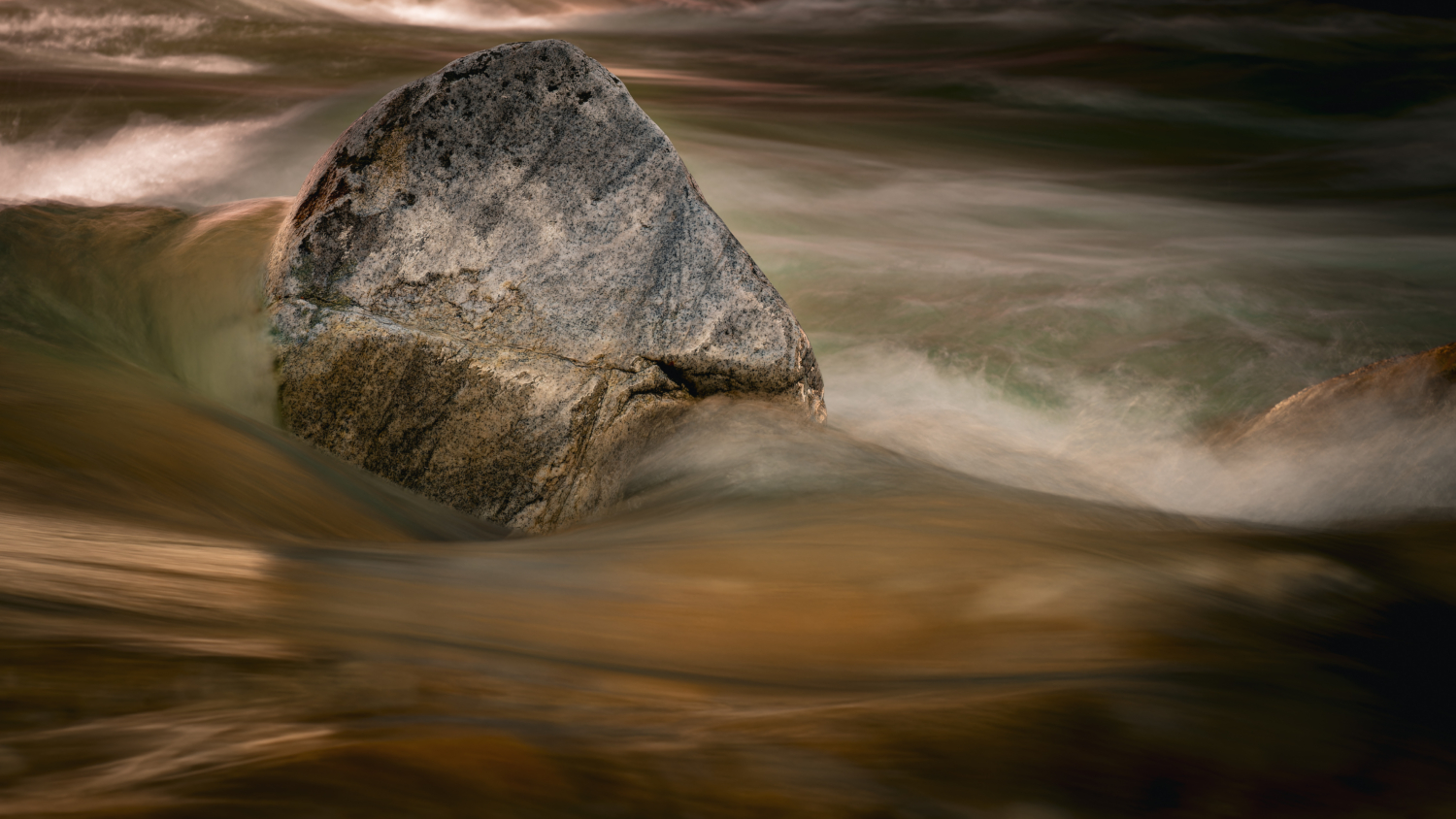 Wasser eines Bergbaches, welches einen Stein umfliesst