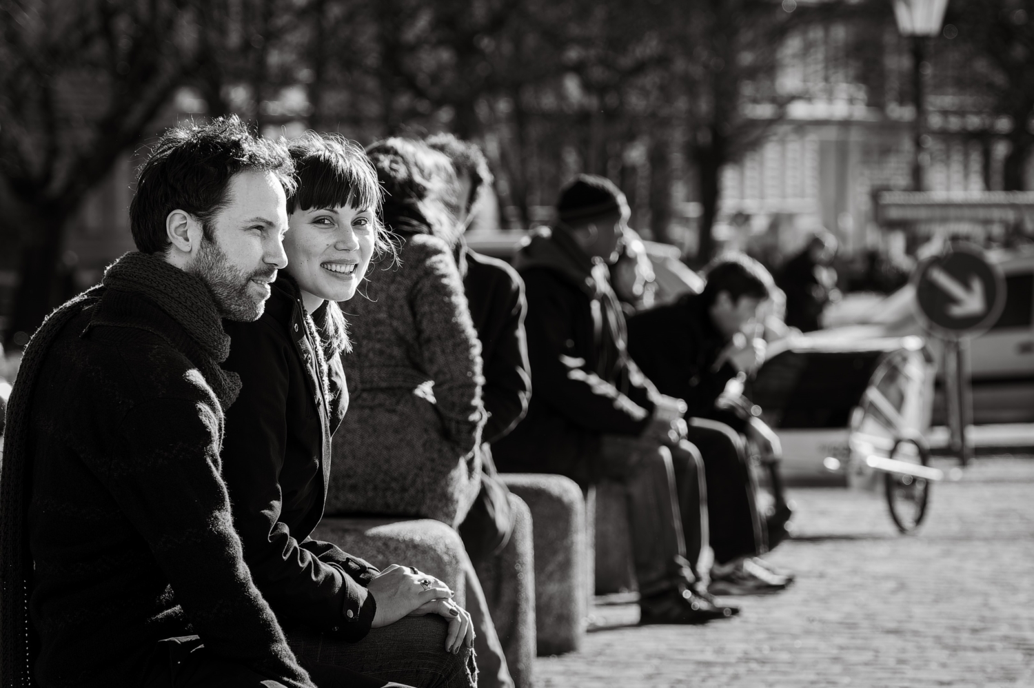 Schwarzweiss-Strassenszene mit sitzendem Paar und Lächeln in die Kamera