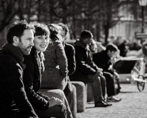 Schwarzweiss-Strassenszene mit sitzendem Paar und Lächeln in die Kamera