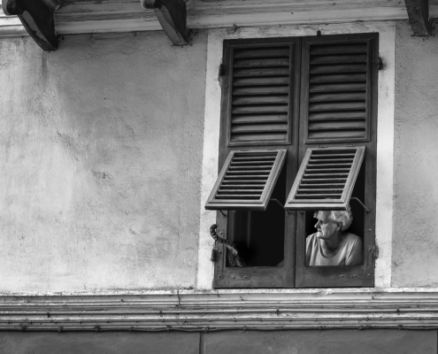 Schwarzweiss-Strassenszene, ältere Dame mit Katze am Fenster