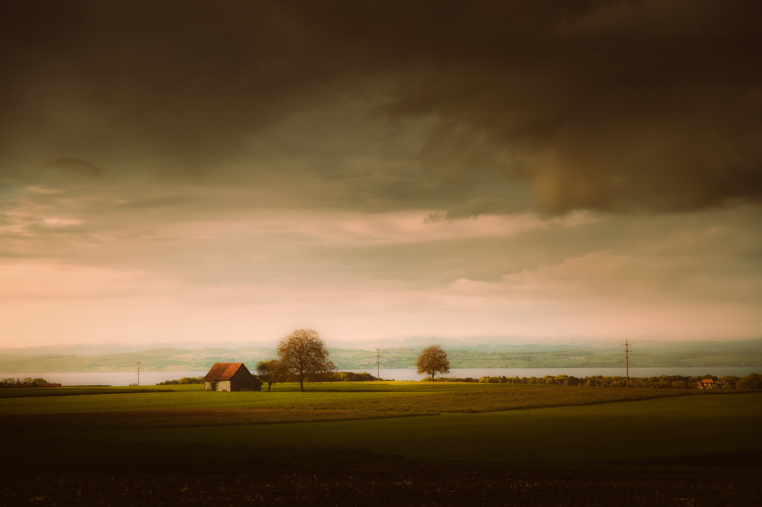Thurgauer Landschaft mit düster-stimmungsvollem Abendhimmel und Sicht auf das deutsche Bodenseeufer