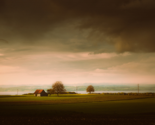 Thurgauer Landschaft mit düster-stimmungsvollem Abendhimmel und Sicht auf das deutsche Bodenseeufer