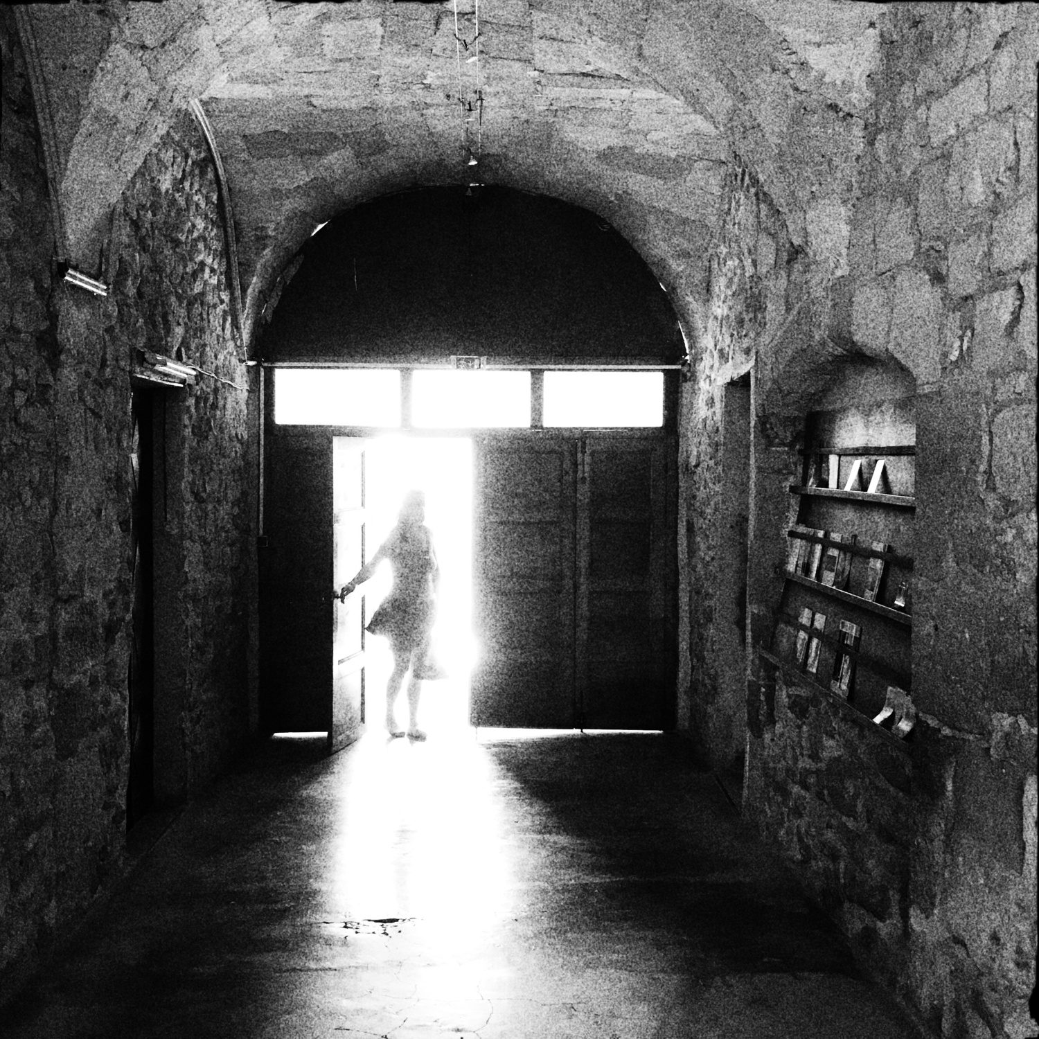 Schwarzweiss-Bild eines schemenhaften, lichtumfluteten Frauenkörpers im Eingang zur Église Saint-Florent in Orange (FR)
