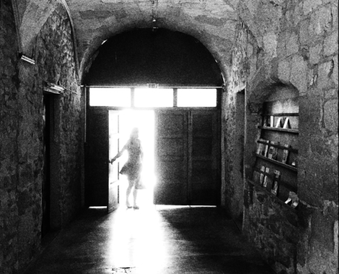 Schwarzweiss-Bild eines schemenhaften, lichtumfluteten Frauenkörpers im Eingang zur Église Saint-Florent in Orange (FR)